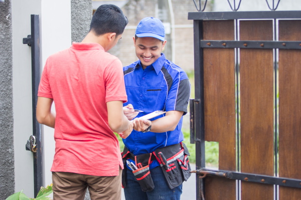 Smiling techinician in blue uniform coming to customer house